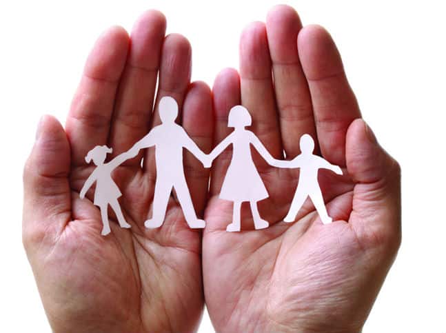 A pair of hands palm side up hold a little paper cutout of a family for Setting up a Trust